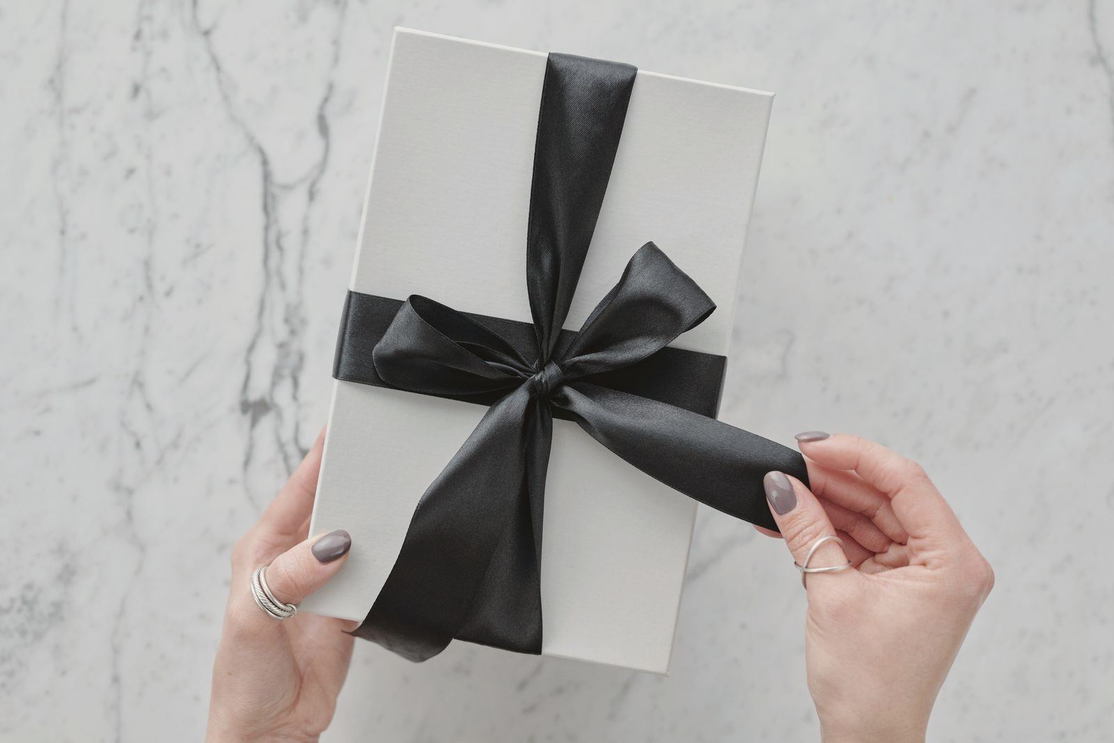 A sleek white present tied with a black satin ribbon, providing a touch of luxury. Ideal for gift themes.